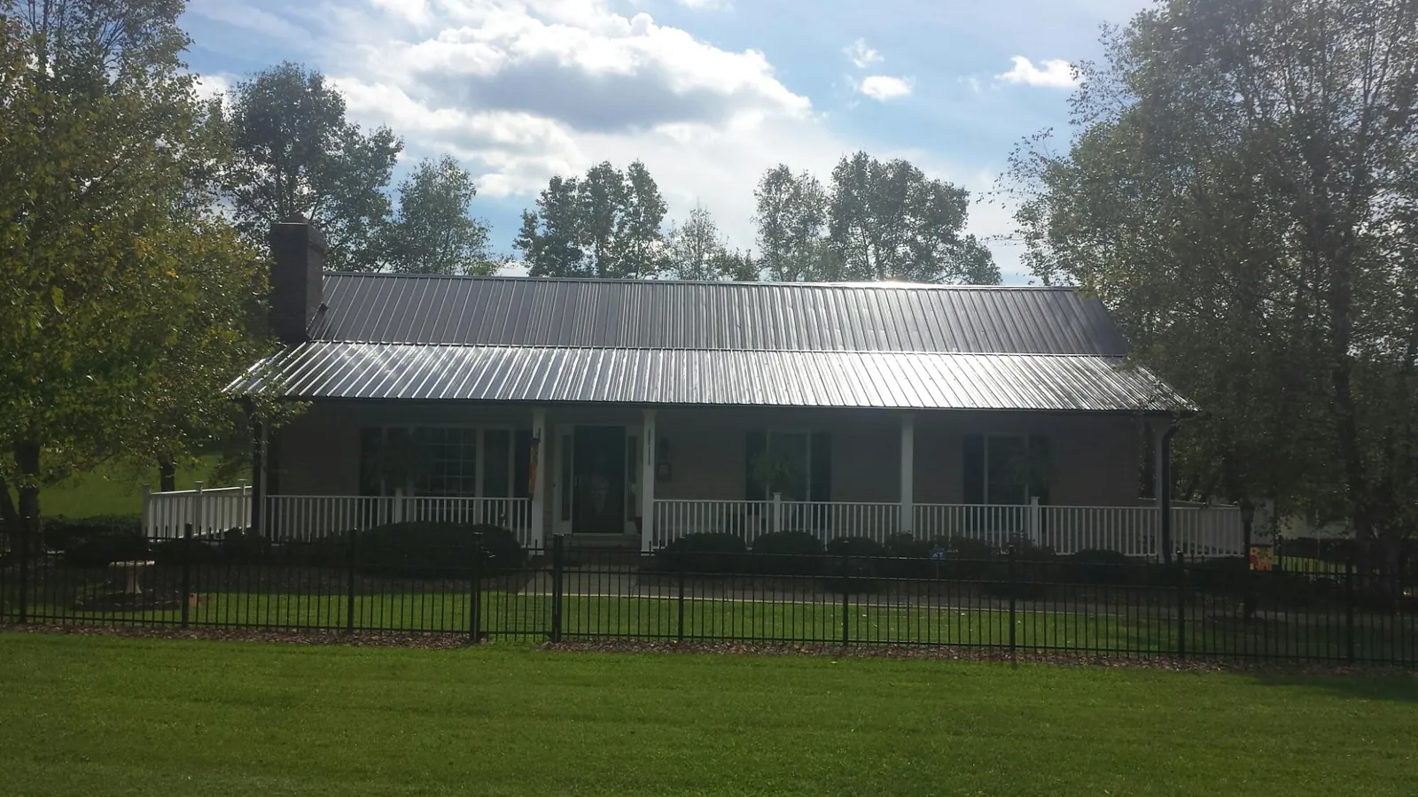 Gray metal roof on a brick ranch with a full width front porch — Gutter Guard Installation work by our crew in Newark